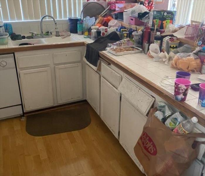 A kitchen with white cabinets and black counter tops. Things on top of the counters.