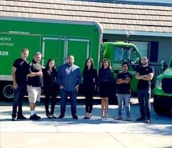 Our team of ladies and gentlemen standing in front of our green SERVPRO trucks.